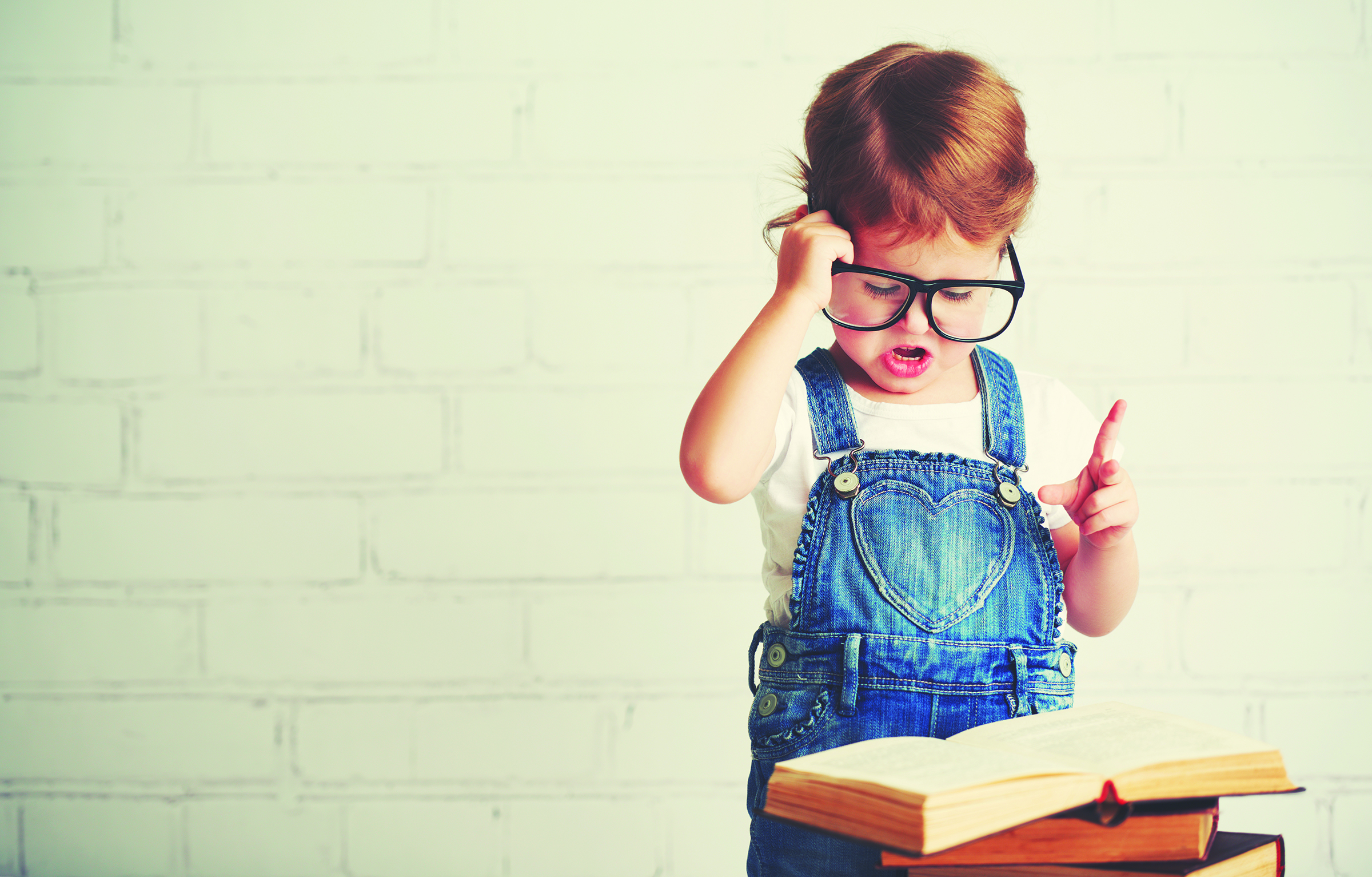 happy child little girl with glasses reading a books
