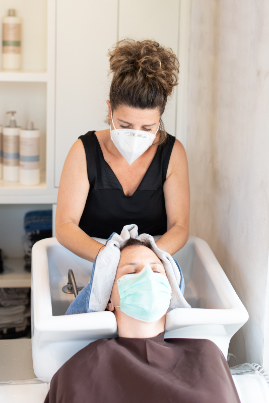 person getting hair washed at salon wearing mask