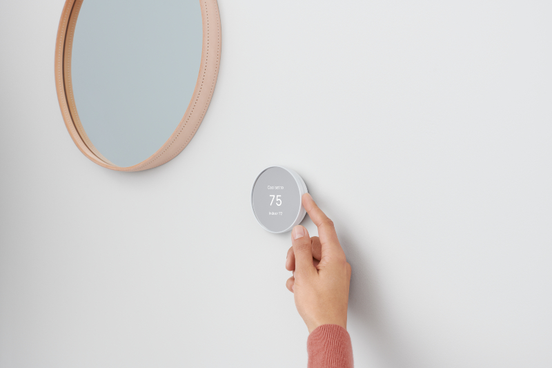 person adjusting temperature on smart home thermostat