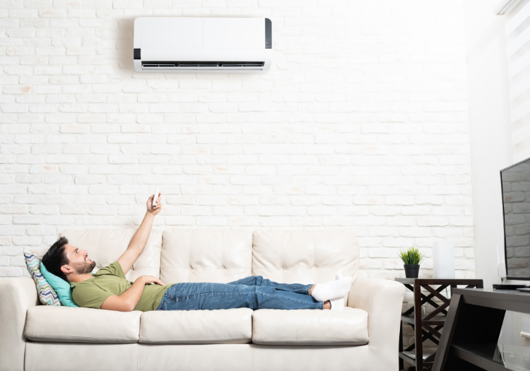 Ductless HVAC Systems: Person turns on air conditioner unit from the couch.