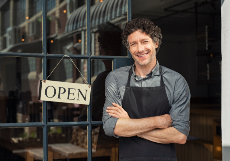 Restaurant owner standing in front of open sigh
